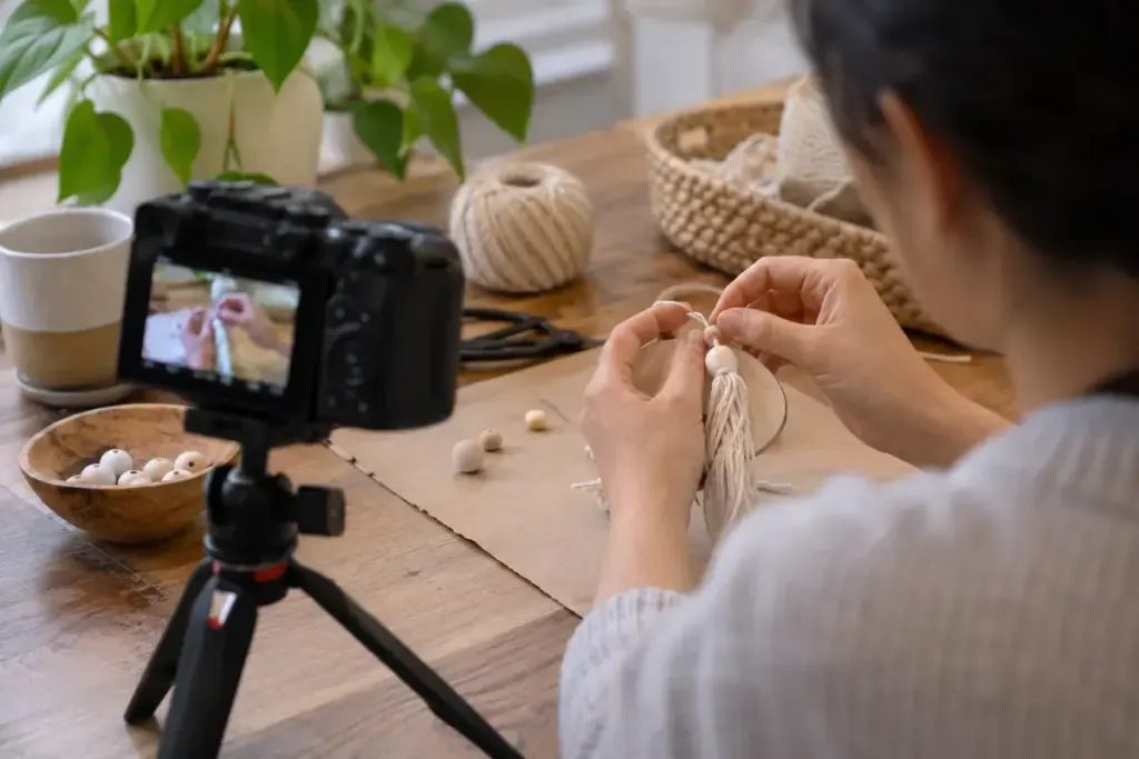 A creator filming a close up of hands assembling a simple craft with a small camera.